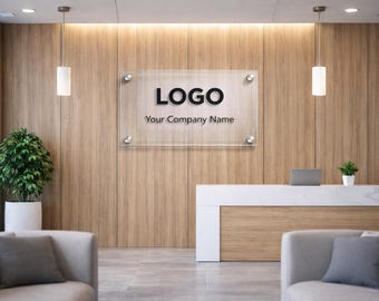 Könnte beinhalten: Ein Empfangsbereich mit einer Holzpaneelwand und einem durchsichtigen Glasschild mit der Aufschrift "LOGO" und "Your Company Name". Ein weißer Empfangstresen, zwei graue Sofas und eine Topfpflanze sind ebenfalls zu sehen.