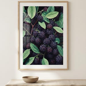May include: A framed print showing a close-up of blackberries on a vine with green leaves. The berries are a deep purple colour, and the leaves are a vibrant green. The artwork is set in a light-coloured wooden frame.