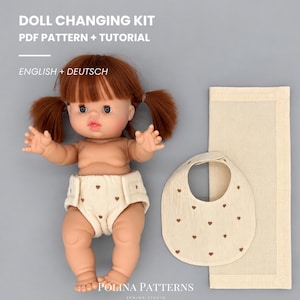 Könnte beinhalten: Eine Puppe mit einer cremefarbenen Windel mit braunem Herzmuster, dazu ein passendes Lätzchen und ein rechteckiges Tuch. Der Text lautet: DOLL CHANGING KIT PDF PATTERN + TUTORIAL ENGLISH + DEUTSCH POLINA PATTERNS SEWING STUDIO.