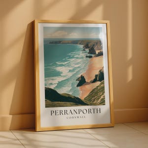 May include: A framed wall art print featuring a coastal landscape of Perranporth, Cornwall. The illustration depicts a sandy beach, turquoise ocean waves, and rocky cliffs under a blue sky with clouds. The text PERRANPORTH CORNWALL is printed below.
