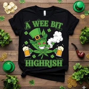 Könnte beinhalten: Schwarzes T-Shirt mit einer Grafik, die ein Cannabisblatt mit einem grünen Koboldhut zeigt, das eine Zigarette raucht und zwei Bierkrüge hält. Der Text lautet "A Wee Bit Highrish".