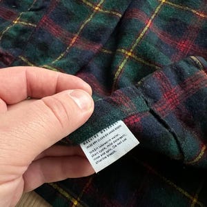 May include: A white ceramic mug with a black handle and the text "But First, Coffee" in a black, handwritten-style font. The mug is on a white surface.