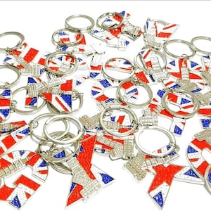 Peut inclure: Plusieurs porte-clés avec le drapeau britannique rouge, blanc et bleu. Les porte-clés ont des détails en métal argenté et présentent diverses formes, notamment le drapeau, une tour et des motifs circulaires.