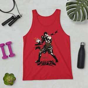 Könnte beinhalten: Rotes Tanktop mit einer Grafik eines Boxers in Aktion, mit schwarz-weißen Akzenten. Das Design enthält stilisierte Elemente und Text am unteren Rand. Zubehör: Kurzhanteln, Springseil, Pflanze und eine schwarze Wasserflasche.