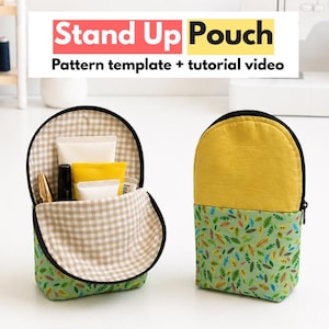 May include: Two fabric stand up pouches with a zipper closure. One pouch is open, revealing a beige and white checkered interior lining holding various tubes. The other pouch is closed, featuring a yellow top and a green leaf-patterned base.