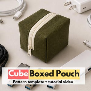 May include: An olive green fabric cube-shaped pouch with a cream-colored zipper, surrounded by various white and black electronic charging cables, power adapters, and a USB hub. The text "Cube Boxed Pouch Pattern template + tutorial video" is visible.