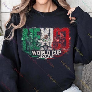 May include: A black crewneck sweatshirt featuring a graphic print of the Mexican flag with the text MEXICO WORLD CUP 2026. The design includes illustrations of soccer players in action and a central soccer ball icon in a distressed style.