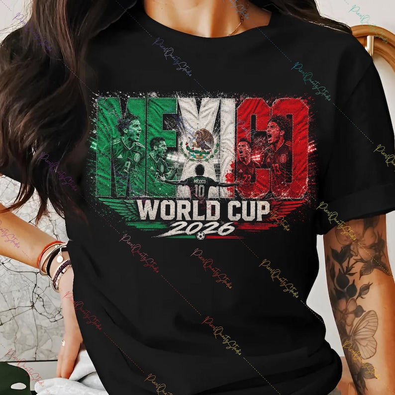 May include: A black t-shirt featuring a graphic design with the word MEXICO in green, white, and red colors. The design includes illustrations of soccer players, the Mexican coat of arms, and the text WORLD CUP 2026 with a small soccer ball icon.