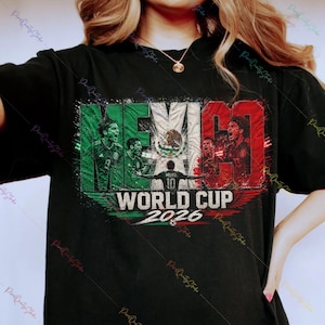 May include: A black t-shirt featuring a graphic print with the text MEXICO WORLD CUP 2026. The design incorporates the colors of the Mexican flag, images of soccer players, and the national emblem, set against a distressed, textured background.