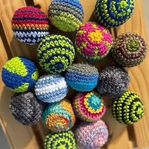 Puede incluir: Una colecci&oacute;n de quince bolas de ganchillo esf&eacute;ricas con diversas combinaciones de colores, incluyendo azul y verde, rojo y amarillo, rosa y amarillo, y gris y negro. Cada bola est&aacute; elaborada con un patr&oacute;n de punto de hilo texturizado variado.
