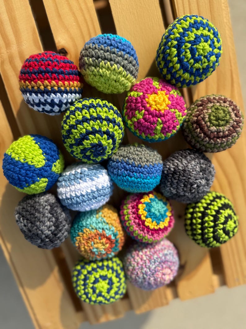 Puede incluir: Una colecci&oacute;n de quince bolas de ganchillo esf&eacute;ricas con diversas combinaciones de colores, incluyendo azul y verde, rojo y amarillo, rosa y amarillo, y gris y negro. Cada bola est&aacute; elaborada con un patr&oacute;n de punto de hilo texturizado variado.