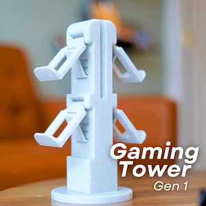 May include: A light grey Gaming Tower Gen 1, a vertical stand for gaming accessories. The tower has multiple angled platforms for holding items. The base is circular, and the text "Gaming Tower Gen 1" is visible on the side.