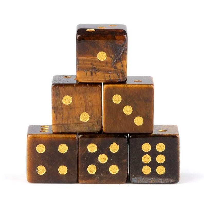 May include: A stack of six brown dice with gold-colored dots. The dice are made of a material with a tiger-eye pattern. Each die has a different number of dots, ranging from one to six.
