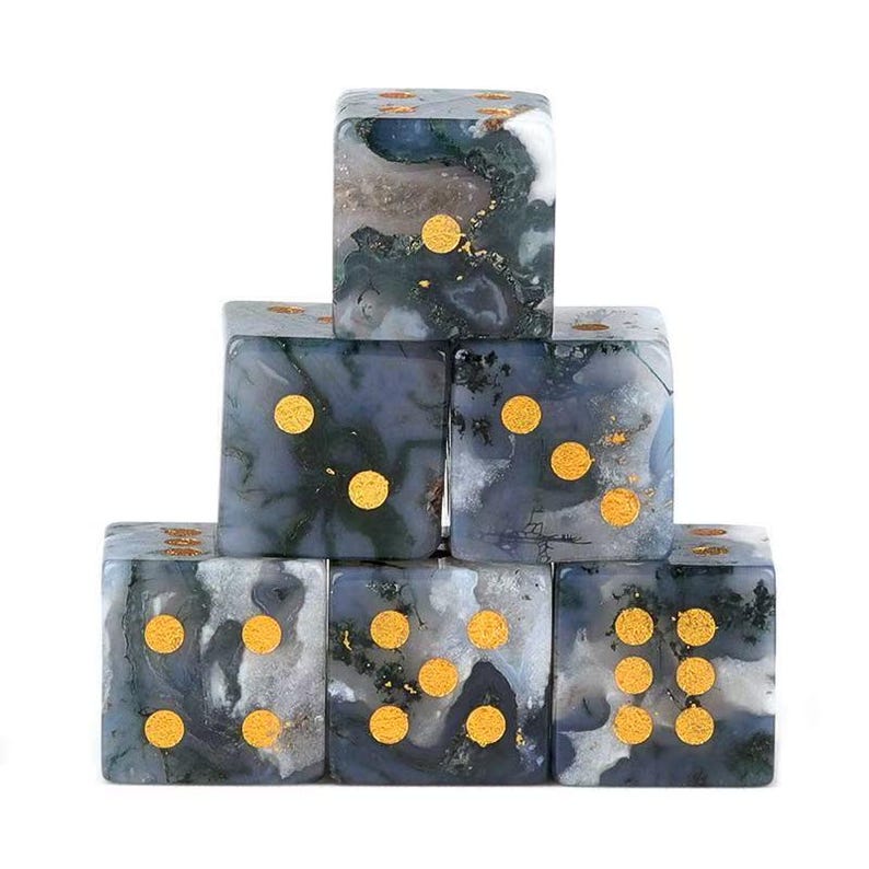 May include: Six dice stacked in a pyramid formation. The dice are made of a marbled gray and white stone with gold-colored pips. The dice are arranged to show different numbers of pips on each face.