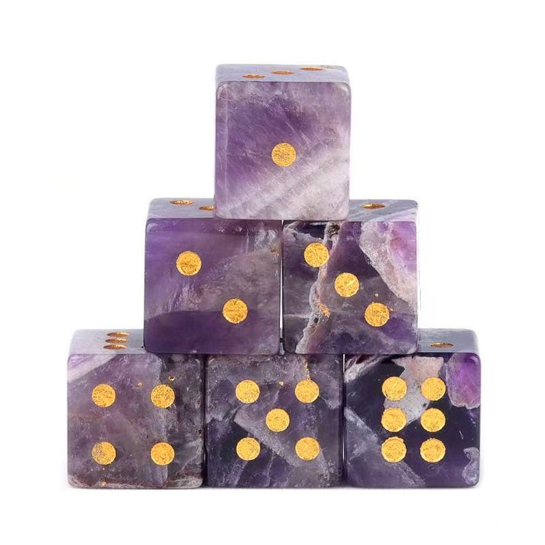 May include: Six amethyst dice stacked in a pyramid formation. Each die features gold-colored dots indicating the numbers. The dice are a mix of purple and white hues, with a polished finish.