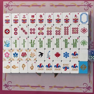May include: A set of white mahjong tiles arranged in a grid, featuring red Chinese numerals with lion faces, red and blue circular patterns, green bamboo stalks, a panda, floral designs, a bird, a fish, a maple leaf, a snowflake, and joker tiles.