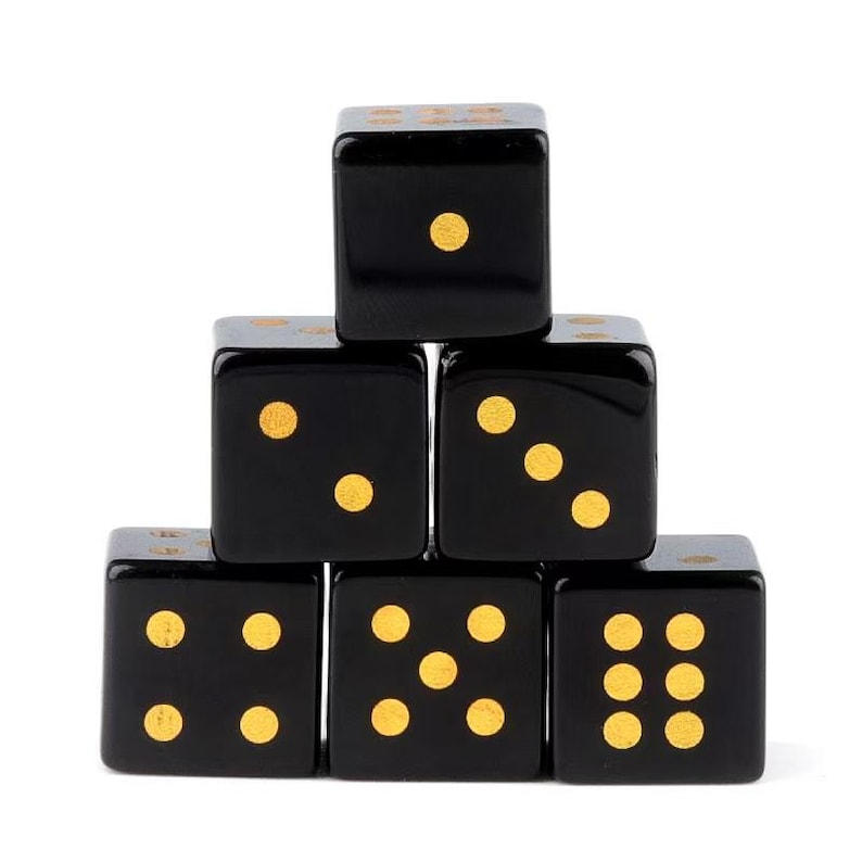 May include: Six black dice with gold dots are stacked in a pyramid shape. Each die displays a different number of dots, ranging from one to six. The dice are arranged against a white background.