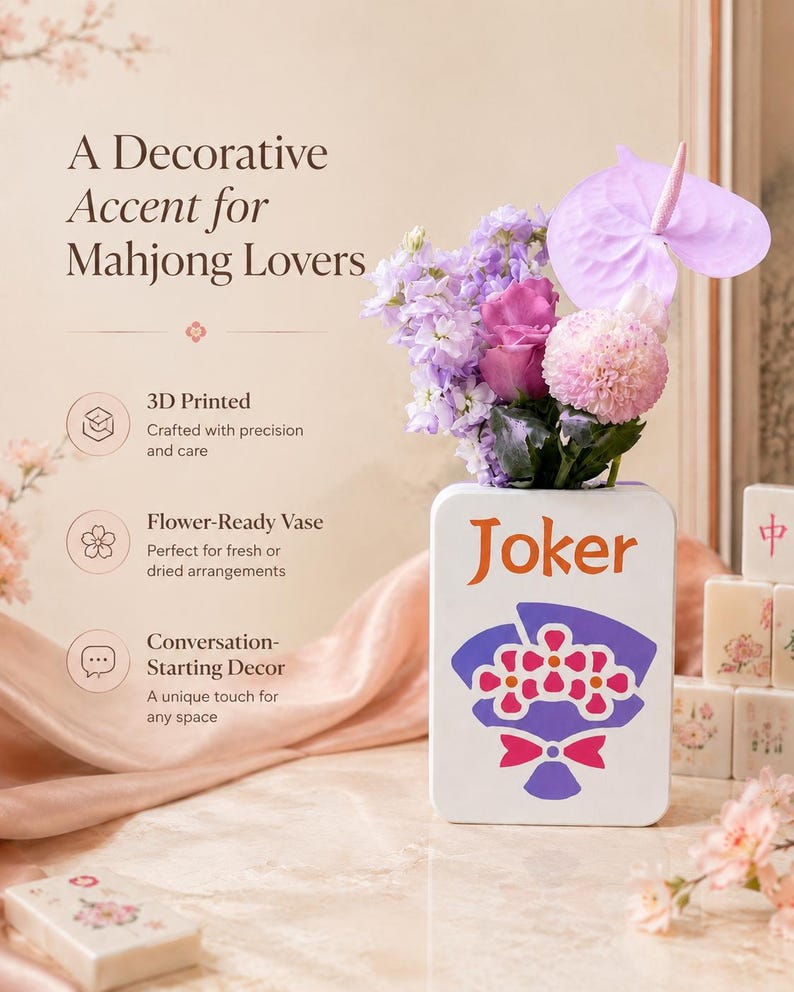 May include: A white, rectangular vase with the word "Joker" in orange, holding a bouquet of purple and pink flowers. The vase has a graphic of flowers and a bow. The text "A Decorative Accent for Mahjong Lovers" is at the top.