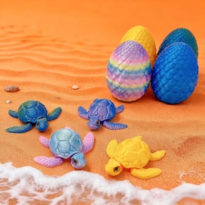 May include: A collection of colorful toy turtles and dragon eggs on a sandy surface. The turtles are in shades of blue, purple, and yellow. The eggs are yellow, blue, and a rainbow of colors.