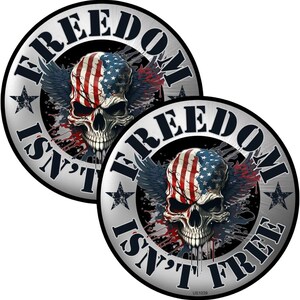 May include: Two round stickers with a skull design. The skull is painted with the American flag and has wings. The text "FREEDOM ISN'T FREE" is printed around the edge of the stickers.