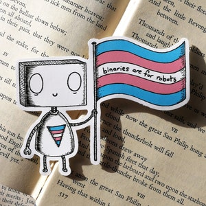 May include: A sticker depicting a robot character holding a flag. The flag displays the text "binaries are for robots" and features pink, white, and blue stripes. The robot wears a shirt with a transgender symbol.