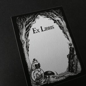 Op de afbeelding: Zwart-witte illustratie van een ex-libris met een kikker die op een paddenstoel zit en een boek leest. Het ex-libris heeft de tekst "Ex Libris" bovenaan.