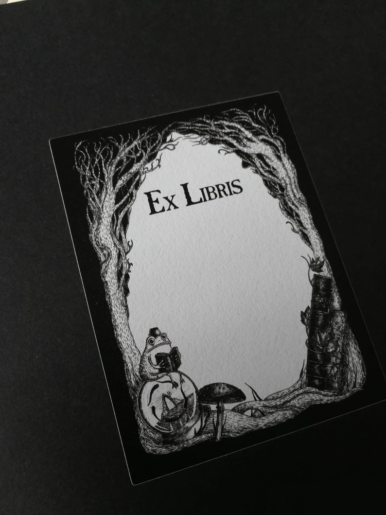 Op de afbeelding: Zwart-witte illustratie van een ex-libris met een kikker die op een paddenstoel zit en een boek leest. Het ex-libris heeft de tekst "Ex Libris" bovenaan.