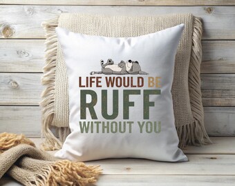 May include: White square throw pillow with the text "LIFE WOULD BE RUFF WITHOUT YOU" in brown and green. A cartoon dog is lying on top of the pillow. The pillow is on a beige fringed pillow and a wooden surface.