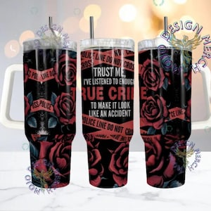 May include: A black tumbler featuring a floral rose design and the text "TRUST ME, I'VE LISTENED TO ENOUGH TRUE CRIME." The design includes red roses and police tape. A black straw is inserted in the lid.