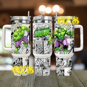 Könnte beinhalten: Ein Edelstahlbecher mit Henkel und Strohhalm, bedruckt mit einer schwarz-weißen Comic-Collage. Das Design zeigt eine große, farbige Illustration des Incredible Hulk mit grüner Haut und violetter Hose sowie den Schriftzug The Incredible Hulk.