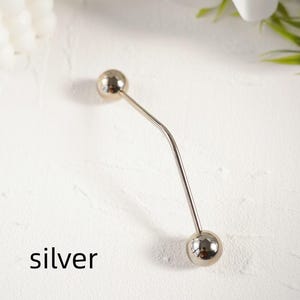 Pu&ograve; includere: Una spilla color argento con un design curvo. Presenta una sfera sferica ad ogni estremit&agrave;. La parola "silver" &egrave; stampata in nero in basso. Questa spilla &egrave; probabilmente utilizzata per scopi decorativi o per fissare gli indumenti.