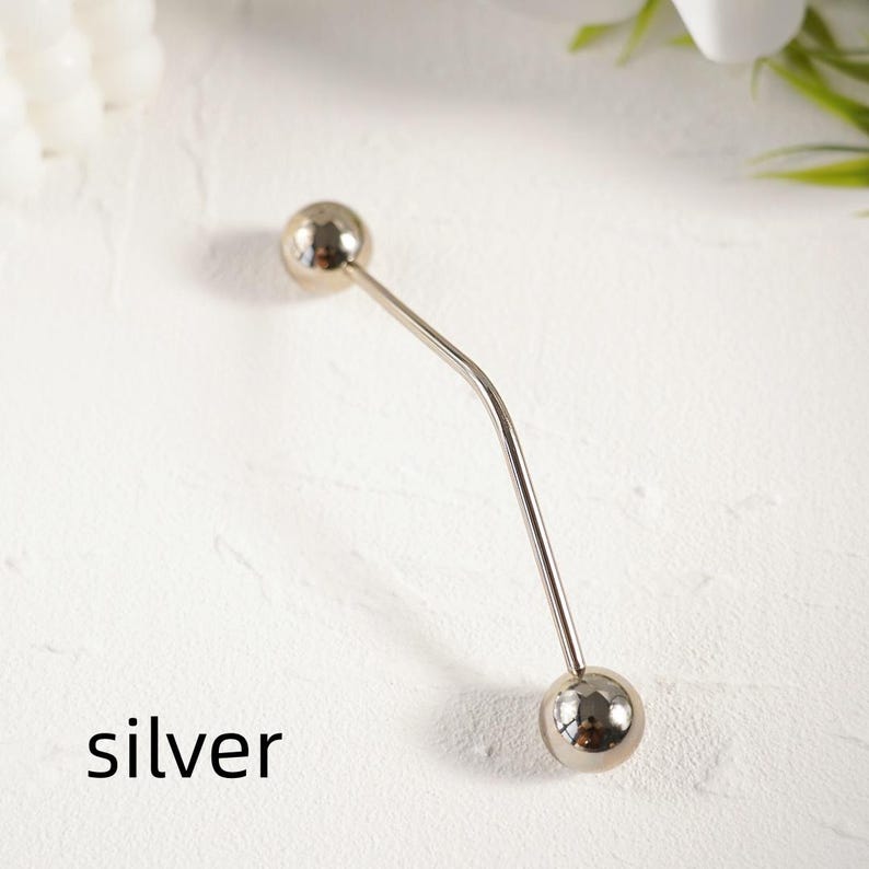 Pu&ograve; includere: Una spilla color argento con un design curvo. Presenta una sfera sferica ad ogni estremit&agrave;. La parola "silver" &egrave; stampata in nero in basso. Questa spilla &egrave; probabilmente utilizzata per scopi decorativi o per fissare gli indumenti.