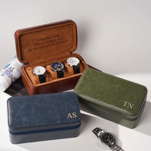 May include: Three rectangular watch cases in brown, navy blue, and olive green leather-like material. The open brown case holds three wristwatches and features the text To My Best Friend With you, ordinary days turn into unforgettable adventures.