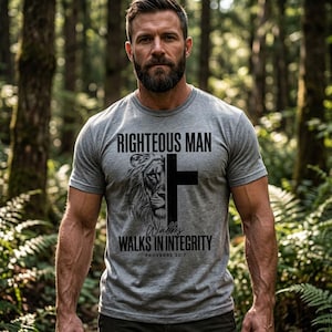 Könnte beinhalten: Graues T-Shirt mit dem Text "RIGHTEOUS MAN" über einem Kreuz- und Löwen-Design. Darunter steht "WALKS IN INTEGRITY" und "PROVERBS 20:7". Das Shirt hat kurze Ärmel.