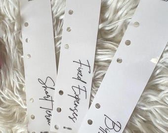 May include: Three white planner inserts with black handwritten text. The inserts are labeled "Short Term", "Fixed Expenses", and "Bills". Each insert has pre-punched holes for binding. The inserts are on a fluffy white surface.