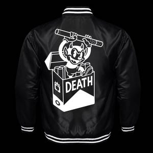 Peut inclure: Une veste universitaire en satin noir avec un motif blanc au dos. Le dessin représente un personnage de diable de dessin animé sortant d'un paquet de cigarettes marqué DEATH, tenant une grosse cigarette au-dessus de sa tête.