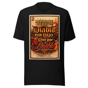 May include: Black t-shirt with a rectangular graphic. The graphic displays the text "MÁS SABE EL Diablo POR VIEJO Que por Diablo" with a devil, skull, and flames in red, orange, and yellow. The number "2" is at the top left of the graphic.