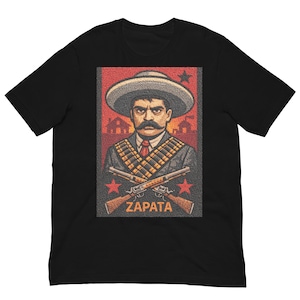 May include: A black t-shirt featuring a graphic print of Emiliano Zapata wearing a sombrero and bandoliers, with two crossed rifles below him. The design includes a red background with silhouettes of buildings, stars, and the text ZAPATA.