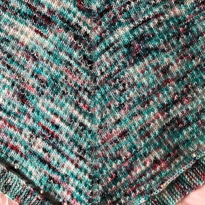 May include: A teal, white, black, and pink knitted shawl with a chevron pattern.