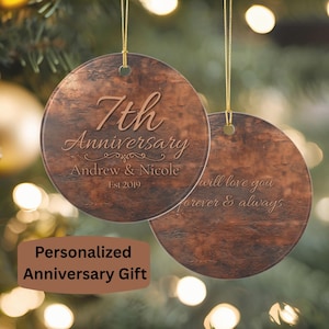 May include: Two round, copper-toned ornaments with a textured finish, each hanging from a gold string. One ornament features the text 7th Anniversary, Andrew & Nicole, and Est 2019. The other ornament displays the text will love you forever & always.
