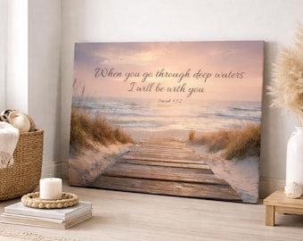 May include: Canvas art print featuring a beach scene with a wooden walkway leading to the ocean. The sky is a blend of pink and orange hues. The text "When you go through deep waters I will be with you" is displayed.