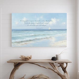 May include: A framed canvas print showing a tranquil seascape with a sailboat under a blue sky. The artwork uses soft blue and white tones, with the text: "Be strong and courageous. Do not fear or be in ahead of them."