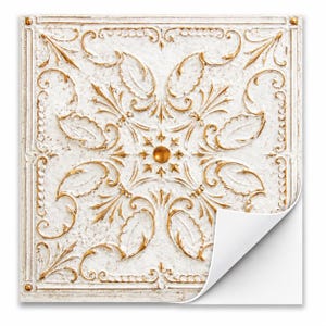 May include: Square, white decorative tile with a gold floral pattern. The tile has a raised, textured design with a central gold orb and corner details. A corner of the tile is peeled back, revealing a white surface.
