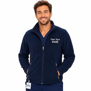 Könnte beinhalten: Eine marineblaue Fleecejacke mit durchgehendem Frontreißverschluss, Stehkragen und zwei Seitentaschen. Der Text "Your Text NAME" ist in Weiß auf der linken Brust gestickt. Ein weißes Identifikationsschild mit "RN" ist am Saum befestigt.