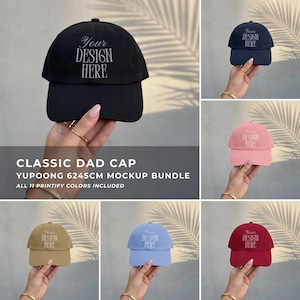 Könnte beinhalten: Eine Kollektion von Yupoong 6245CM Dad Caps in verschiedenen Farben wie Schwarz, Pink, Beige, Hellblau und Rot. Jede Kappe hat einen gebogenen Schirm und den Text Your Design Here auf der Vorderseite. Dies ist ein Mockup-Bundle zur Ansicht.