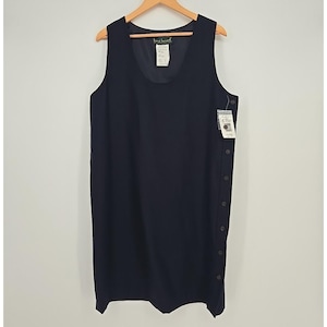 May include: A sleeveless, navy blue dress with a scoop neckline hangs on a wooden hanger. The dress features a row of buttons down the side and a tag attached. The dress is a solid color and appears to be made of a lightweight fabric.