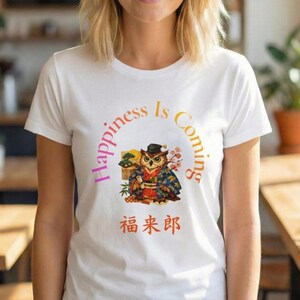 May include: White t-shirt featuring a colorful graphic of an owl in traditional Japanese attire, with the text "Happiness Is Coming" in a semi-circle above the owl. Below the owl is Japanese text.