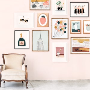 May include: A pink wall gallery with framed artwork featuring illustrations of a strawberry, champagne bottle, ostriches, balloons, a building, a woman on a horse, and a group of women.
