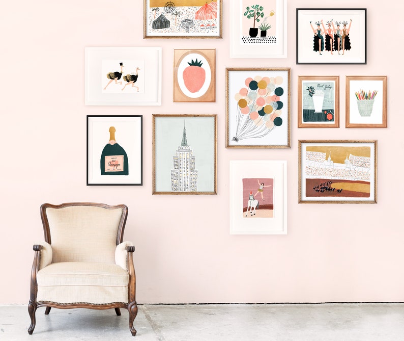 May include: A pink wall gallery with framed artwork featuring illustrations of a strawberry, champagne bottle, ostriches, balloons, a building, a woman on a horse, and a group of women.