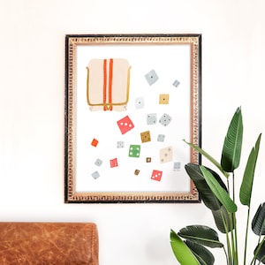 Op de afbeelding: Een ingelijste illustratie van een beige tas met rode en oranje strepen en een strooiing van kleurrijke dobbelstenen in tinten rood, groen, grijs en bruin.
